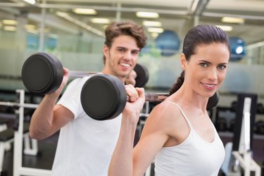 Fit couple lifting barbells together