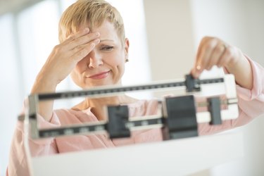 Doubtful Woman Adjusting Weight Scale