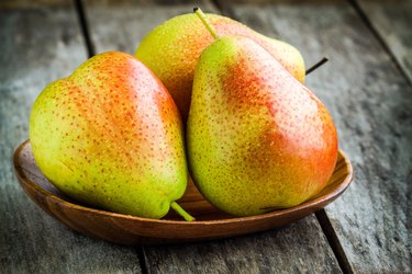 Three fresh ripe organic pears in a wooden bowl