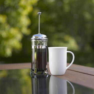 Coffee cup and plunger on table