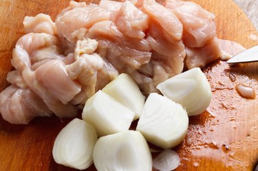 Chicken cubes and onion on the kitchen cutting board