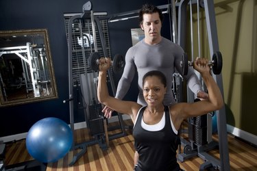 Trainer instructing a young woman with sports equipment in the gym
