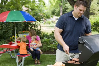 Father cooking at backyard family barbeque