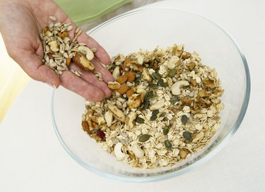 Woman mixing nuts into muesli, close up