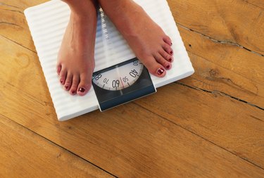 Woman standing on weight scale, low section