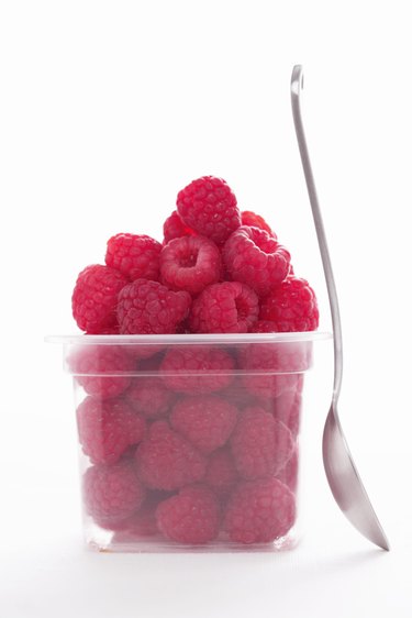 Punnet of raspberries by spoon, close-up