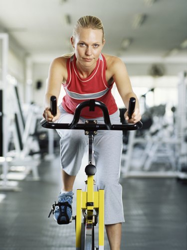 Portrait of a young woman on exercise bike in gym.