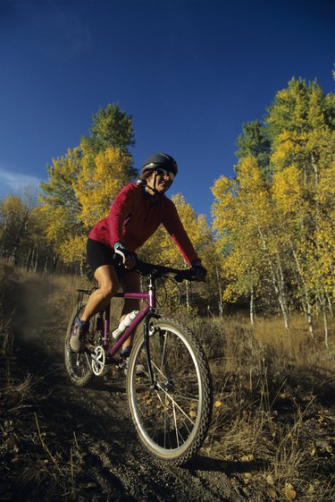 Female mountain biker riding on trail in forest