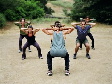 Man leading group of people in boot camp exercises, rear view