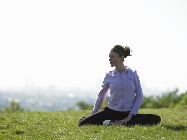 Young woman sitting on grass doing yoga