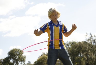 Boy (12-13) playing with plastic hoop in park