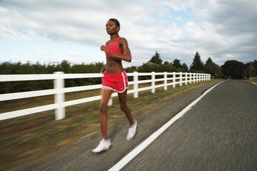 Young woman jogging along country road (blurred motion)