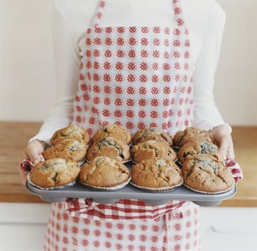 Mid Section View of a Woman Carrying a Baking Tray With Muffins