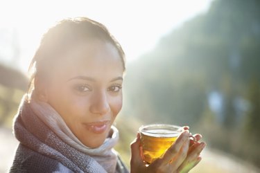 Portrait of smiling woman in scarf drinking cider