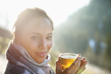 戴着围巾的微笑女子喝苹果酒的肖像