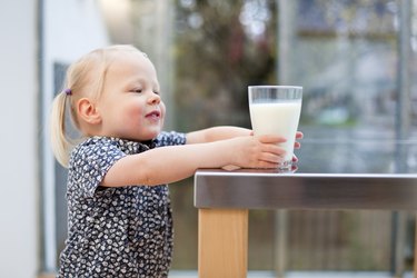 Toddler girl holding glass of milk