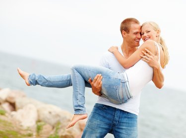 Handsome young man carrying his girlfriend outdoors