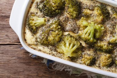 Close-up of broccoli casserole with fresh brocooli on wooden table