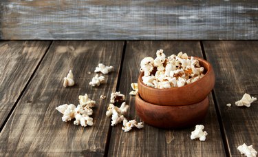 popcorn in wooden bowl on a wood background, selective focus