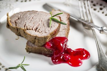 Venison served with cranberry sauce on white plate