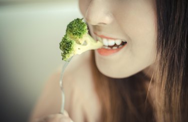 happy smiling  woman eating broccoli