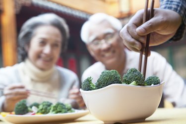 Hand picking up broccoli with chopsticks