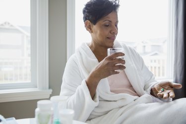 Woman in bathrobe taking vitamins