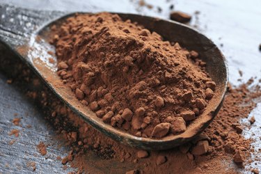 A large wooden spoonful of cacao powder.