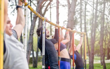 group of young people are competing doing pull ups in local park