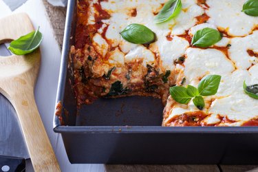 Ricotta cheese oozing between layers of lasagna in a baking pan.