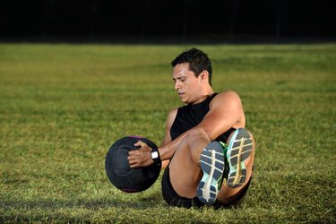 sport man workout on green grass lifting big ball