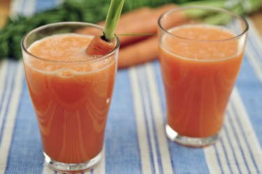 Ginger carrot juice in glass on blue and white table