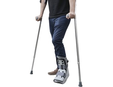 broken leg man wearing ankle support with walking crutches