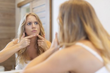 Angry woman squeezing  pimple from face