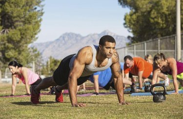 Strong man leading push-ups with exercise group