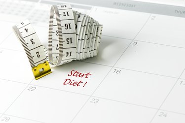 Start diet in red ink on white calendar with tape measure