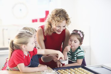 Mid adult woman making cookies with son and daughters