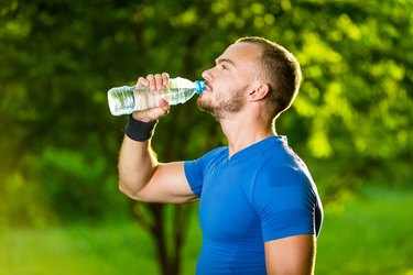 运动成熟的男人用瓶子喝水