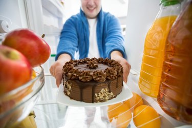 Boy take chocolate cake from fridge