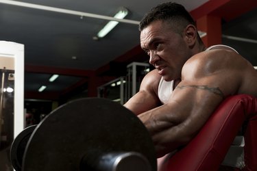 Man In The Gym Exercising Biceps With Barbell