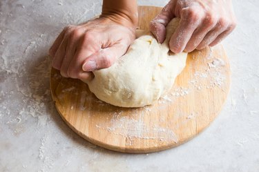 Hands knead dough