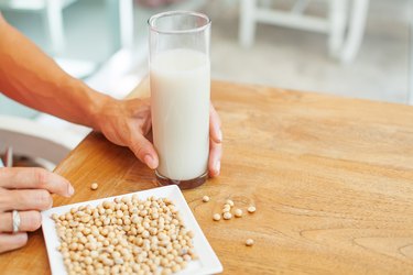 female hand holding a glass of soya milk