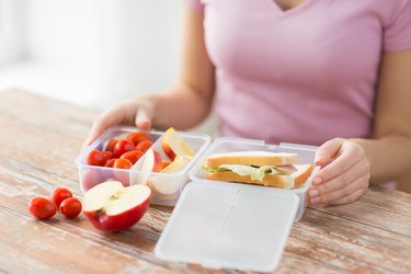 close up of woman with food in plastic container