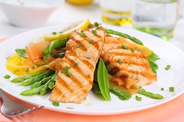 grilled salmon with spring vegetables on white plate, soft focus