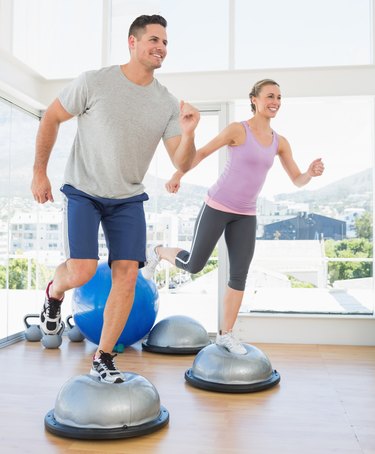 Couple doing step aerobics in fitness studio