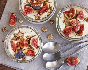 Three bowls of yogurt with figs and walnuts on a linen napkin