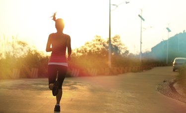 sporty woman morning exercise running on mountain driveway under sunrise