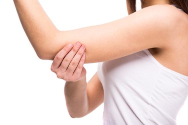 Close-up hand of young woman with a sore elbow on white background.