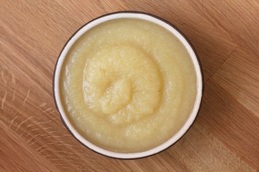 Apple sauce in rustic brown dish on dark wood.