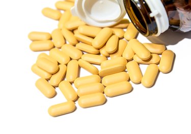 Piles of vitamin tablets drop from brown bottle isolated